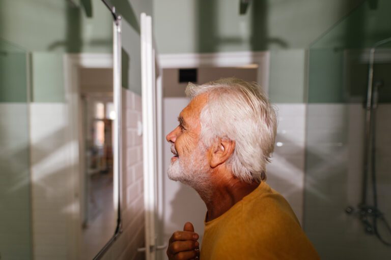 profile view of a smiling senior man looking in the mirror