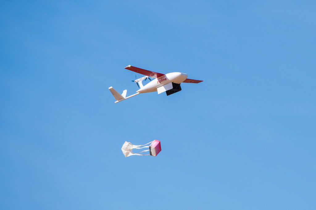 A small plane in a clear sky dropping a package containing blood