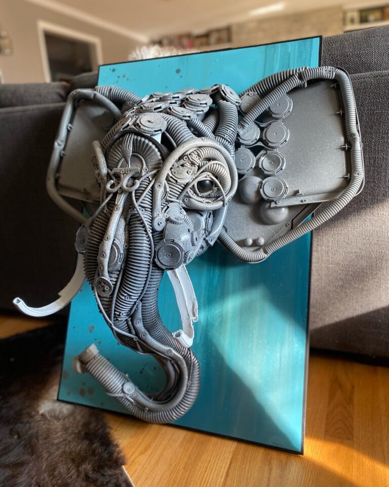 A large sculpture of an elephant head on a blue background by Stephanie Hongo