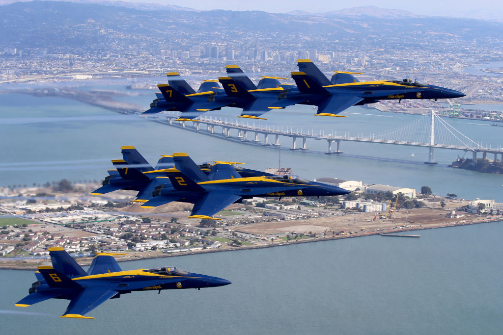 The Blue Angels fly in formation over the San Francisco Bay, with Treasure Island and the city of Oakland in the background.