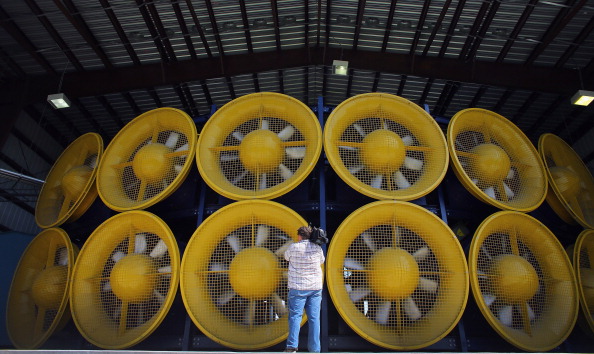 A videographer stands in front of twelve massive fans, that create what is called a Wall of Wind