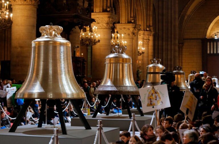People gather around the big shiny bells of Notre-Dame de Paris Cathedral during their blessing mass