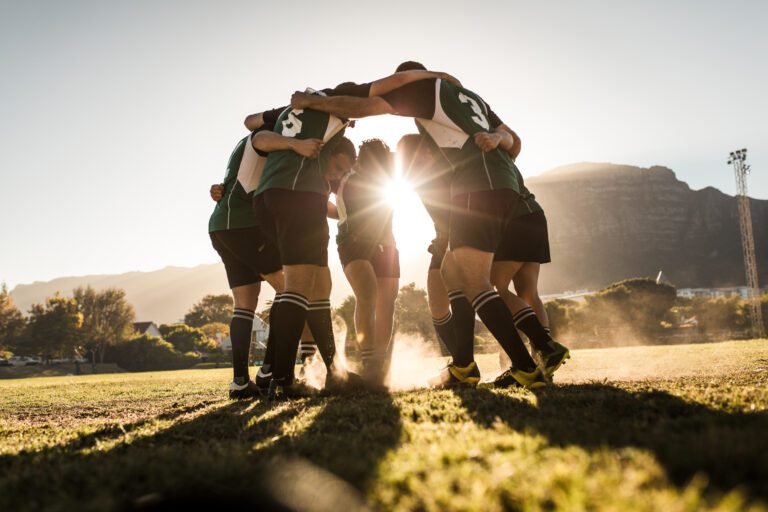 Rugby Team Standing In A Huddle And Rubbing Their Feet into the grass