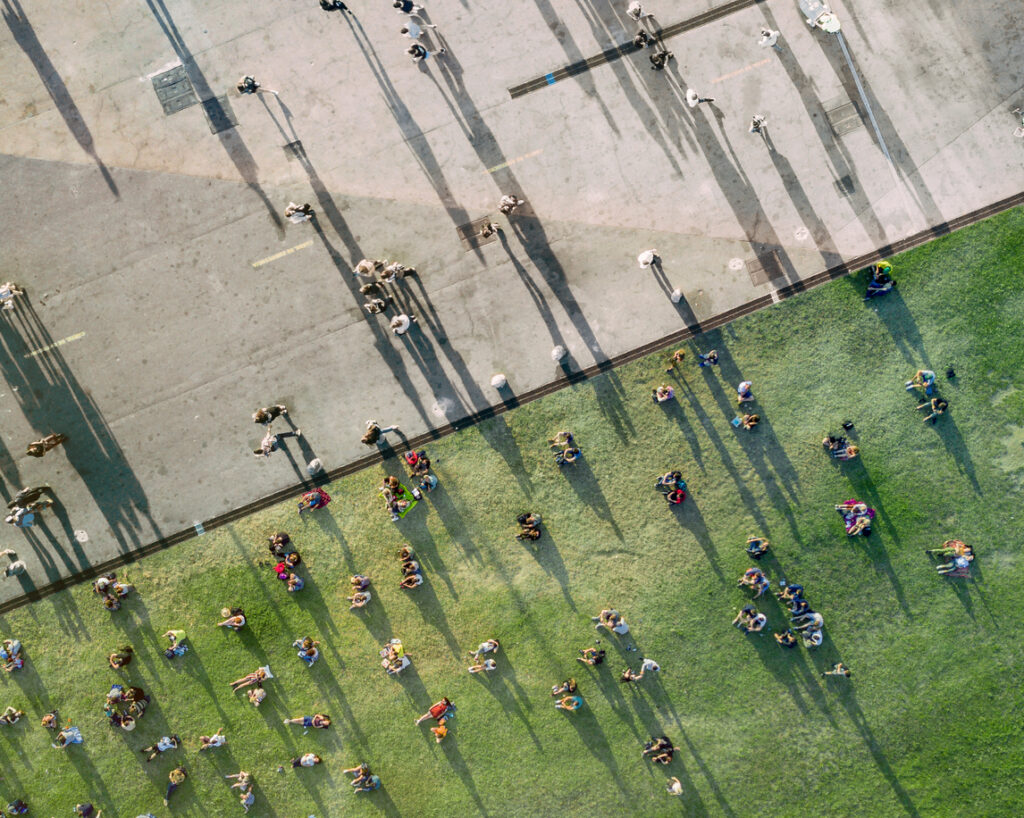 An aerial view of people sunbathing in the park, some on the cement and the others on the grass