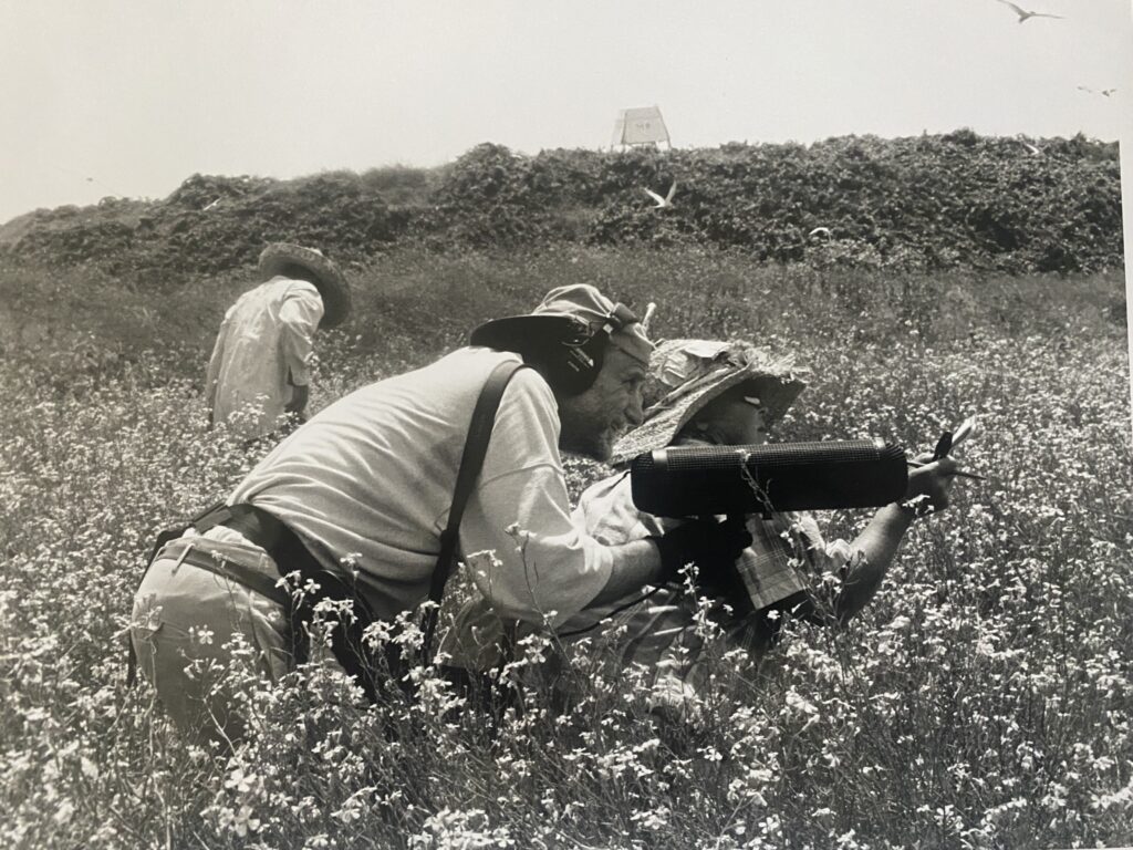 a black and white photo of Jim Metzner recording in a field on Great Gull Island