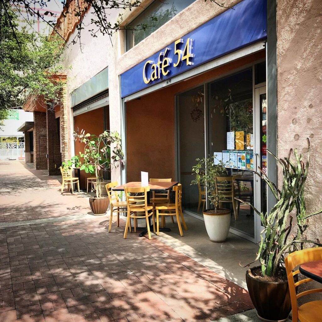 an exterior view of Café 54 on a sunday day with benches outside. The cafe provides employment training and opportunities for people with mental health challenges and disabilities