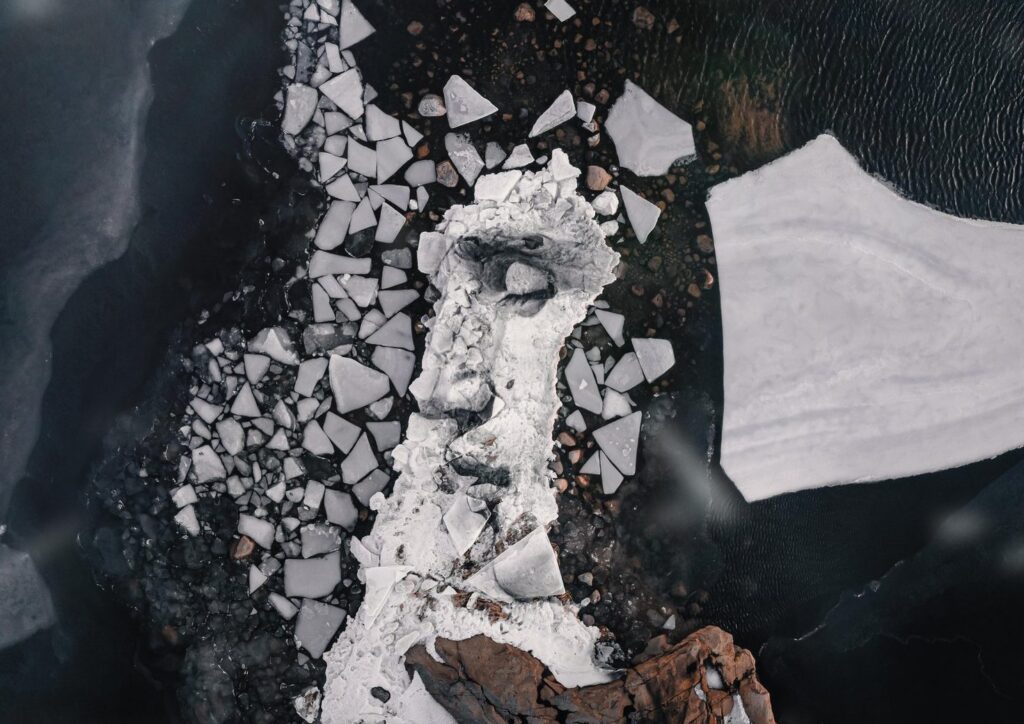 an aerial view of a massive ice portrait featuring the profile of a mans face with closed eyes