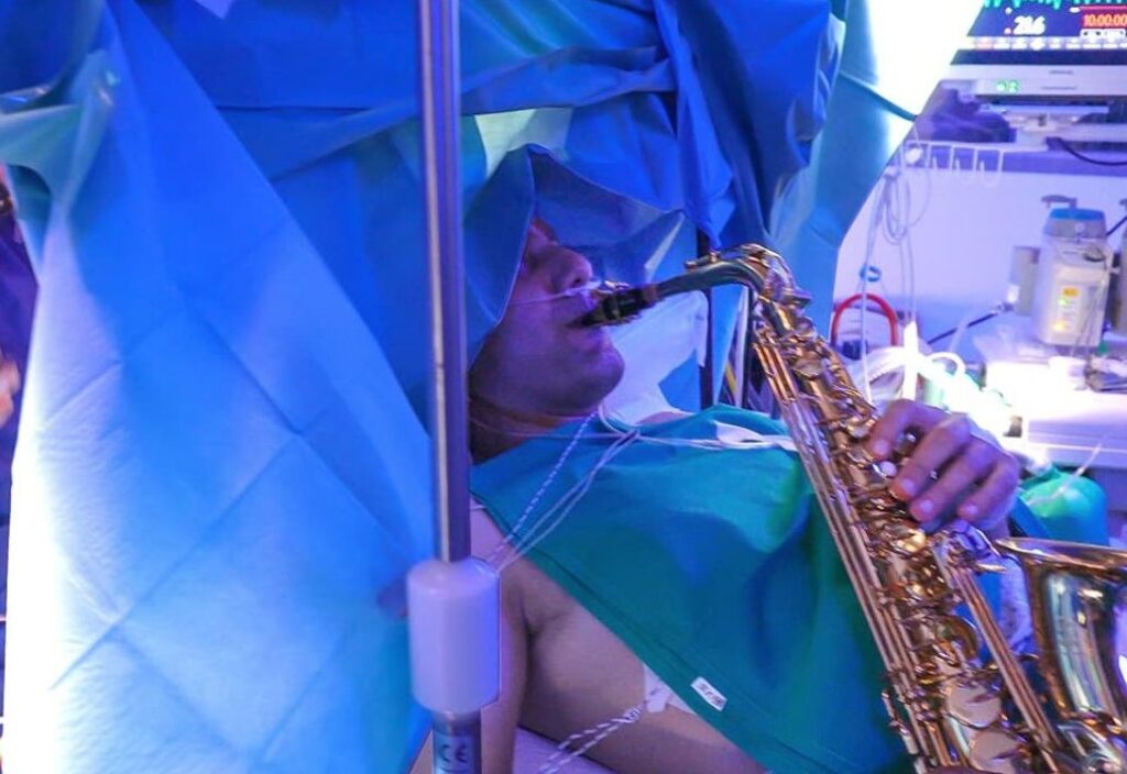 a photo of a patient on an operating table playing saxophone while doctors perform brain surgery on him