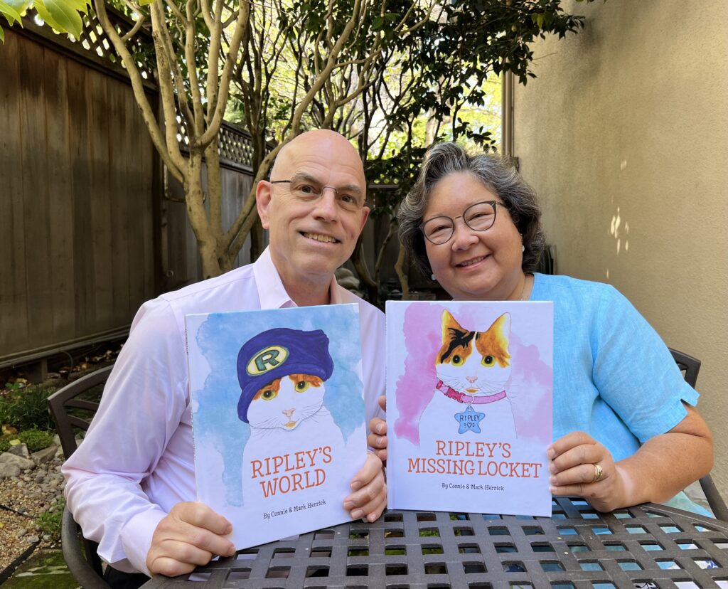 a photo of Connie and Mark Kerrick holding up two of their children's books about their cat Ripley