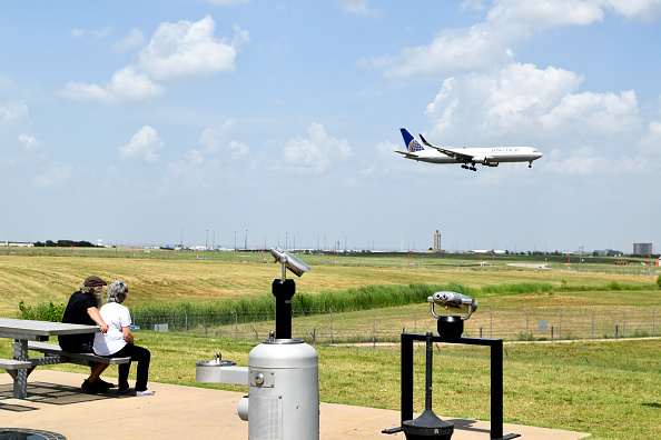 A husband and wife at the DFW Airport observation area watch a United Airlines jet plane landing. (Photo by: HUM Images/Universal Images Group via Getty Images)