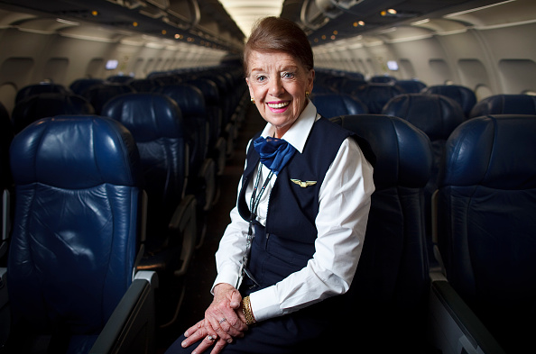 A photo of Bette nash, the world's oldest flight attendant, smiling and facing the camera aboard a plane