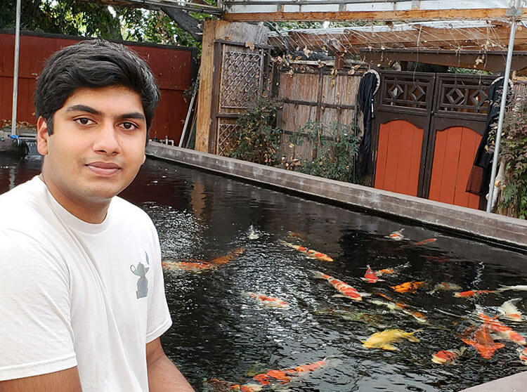 Indeever Madireddy stands in front of a pond of angelfish, the species whose genome he sequenced