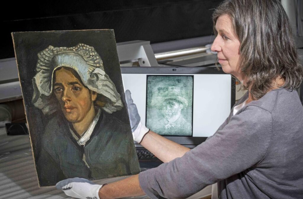 a conservator sits with "Head of a Peasant Woman," the van Gogh painting behind which a hidden self-portrait was discovered. An X-ray image of the self-portrait is displayed on a screen next to her.