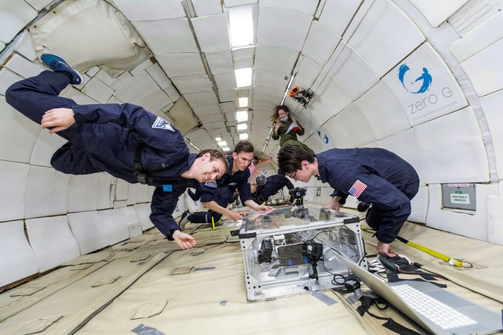 researchers working on the black box extrusion process smile as they hover above the box in low-gravity on a flight test