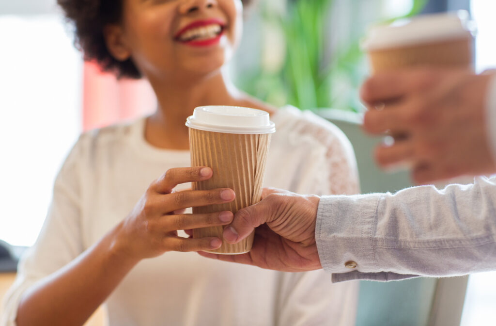 close up of happy african american woman hand taking coffee cup from man on random acts of kindness day