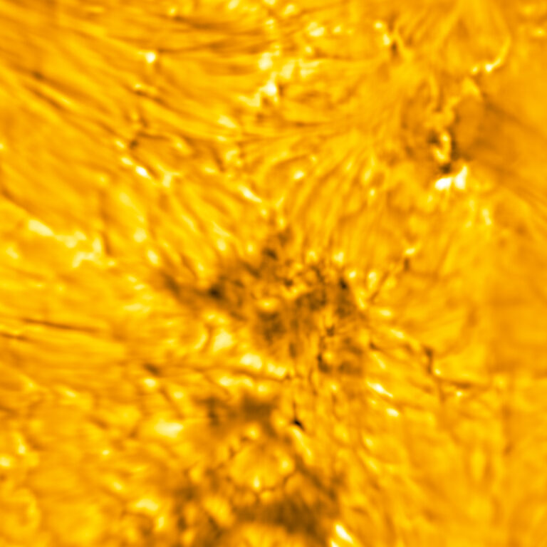 The lower atmosphere (chromosphere) of the Sun exists above the Sun’s surface (photosphere). In this image, dark, fine threads (fibrils) are visible in the chromosphere emanating from sources in the photosphere – notably, the dark pores/umbral fragments and their fine structure. A pore is a concentration of magnetic field where conditions are not met to form a penumbra. Pores are essentially sunspots that have not had or will never have a penumbra. Penumbra: The brighter, surrounding region of a sunspot’s umbra characterized by bright filamentary structures.