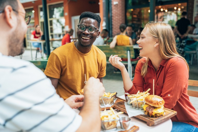 Friends eating burgers and fries and have fun in outdoor restaurant