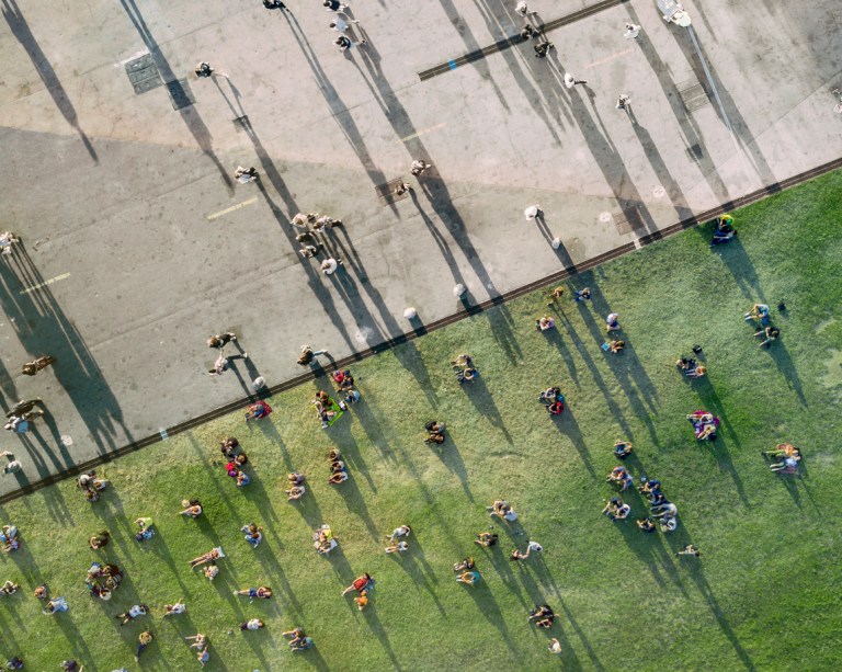 An aerial view of people sunbathing in the park, some on the cement and the others on the grass