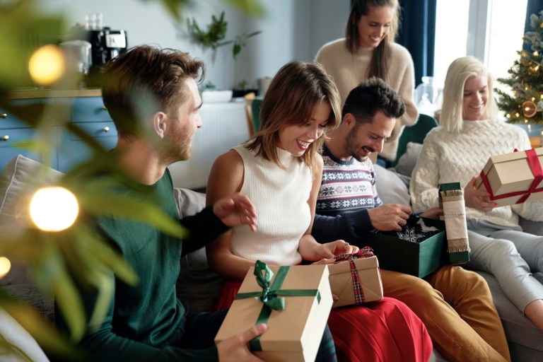 Group of friends on a couch opening Christmas gifts