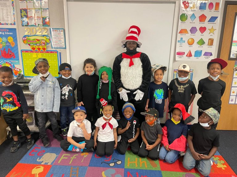 a group of smiling kids sit and stand together in a classroom