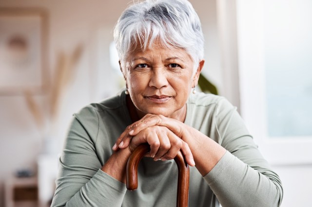 An older woman with a positive outlook on aging stares into the camera, smiling.